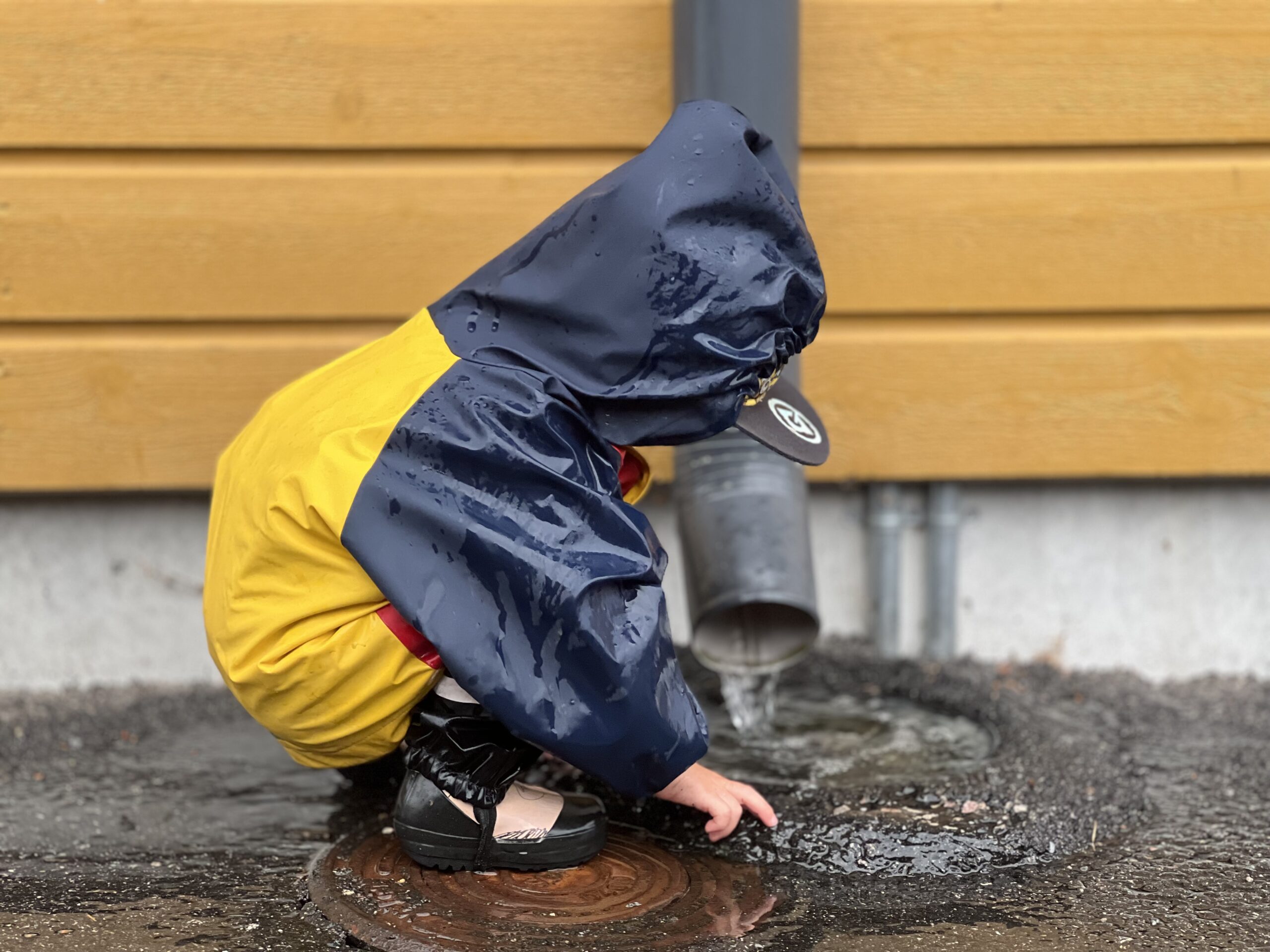 Pieni lapsi vesisateessa kuravaatteet päällä